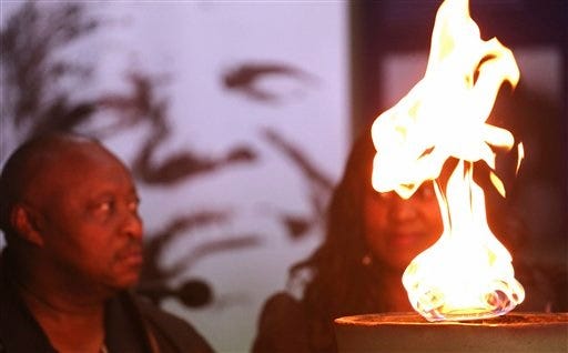 Mzwandile Vena, left, looks at a candle lit for the late South African president Nelson Mandela, photo center back, during a remembrance ceremony in Qunu, South Africa, Saturday, Dec. 7, 2013. Mandela, 95, anti-apartheid icon and former South African president, has died. The Nobel Peace Prize winner's death was announced by South African President Jacob Zuma on Thursday. (AP Photo/Schalk van Zuydam)