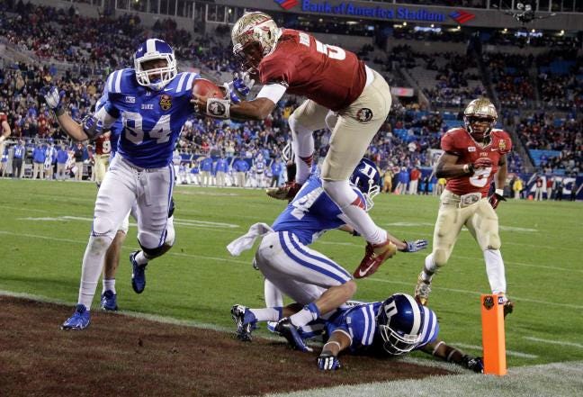 Florida State’s Jameis Winston leaps over Duke’s Bryon Fields (14) for a touchdown in the second half of the Seminoles’ 45-7 victory in the ACC championship on Saturday night. Auburn and Florida State will play for the national title on Jan. 6 in Pasadena, Calif.