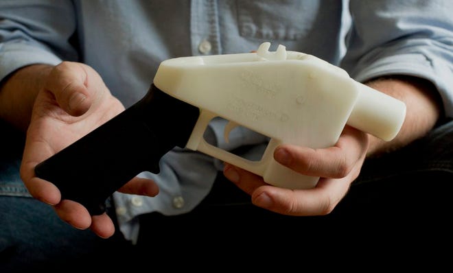 This photo taken May 10, 2013 shows Cody Wilson holding what he calls a Liberator pistol that was completely made on a 3-D-printer at his home in Austin, Texas. Congress is extending a ban on plastic firearms that can slip past airport and school metal detectors and X-ray machines, a bittersweet moment for gun control advocates just before the first anniversary of the mass killing at a Connecticut elementary school. (AP Photo/Austin American Statesman, Jay Janner)