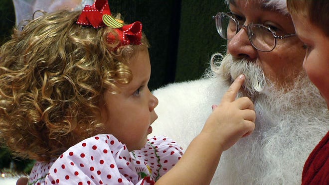In Nov. 29, 2013 photo taken from video, Ava Moser, 2, touches “Santa” Cliff Snider’s mustache as her brother Landon, 5, looks on in Raleigh, N.C. Snider began studying how to be Santa in 1996 and thinks children deserve as authentic an experience as he can give them.