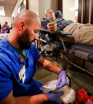 File: Jeremy Whitson checks labels as Kip Henry donates blood. [The Oklahoman archives]