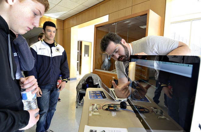 Matt Smollinger, a mobile platform architect, explains computer code to New Hope-Solebury High School students Josh Elefante and Marcus Hems during an interactive presentation Thursday. The program was part of Computer Science Education Week, designed to inspire students to pursue careers in technology.