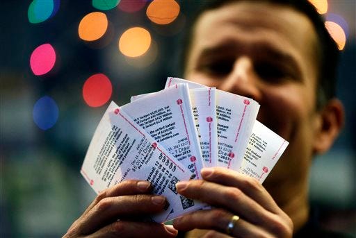 During an interview with the Associated Press, Chad Cuneo displays Mega Millions lottery tickets he purchased at a newsstand Friday, Dec. 13, 2013, in Philadelphia. Superstition didn't deter players hoping that Friday the 13th will bring them good luck in the Mega Millions game as heavy sales prompted lottery officials to boost the estimated jackpot to $425 million. (AP Photo/Matt Rourke)