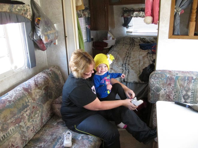Kristin Dale puts shoes on her 18-month-old daughter, Aubrey, in the family's trailer on Dec. 12 at Campbellsville, Ky. The family of four has been living at an RV campground while Kristin's husband and Aubrey's father works full time as a seasonal employee at the Amazon.com warehouse in the Kentucky town.