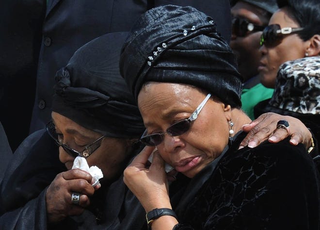 Former South African President Nelson Mandela's widow Graca Machel, right, and Winnie Madikizela-Mandela, Nelson Mandela's former wife, wipe their tears as the former president's casket arrives at Mthatha Airport in Mthatha, South Africa, Saturday, Dec. 14, 2013. The funeral service for Nelson Mandela will be held in his home town of Qunu on Sunday.
