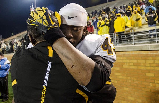 James Kenan's Keevon Miller (right) hugs Devonte Faison on the sideline as the clock winds down during the 1AA state championship game in Winston-Salem on Saturday, Dec. 14, 2013. The Tigers beat West Montgomery 42-14. Photo by Melissa Melvin-Rodriguez