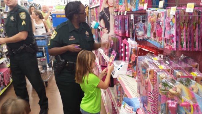 Lake County Sheriff’s deputy Soni Campbell helps 6-year-old Destiny Stokes shop for toys Saturday at a Walmart in Clermont, as part of the annual Shop with a Cop program.