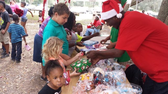 Andre Williams, with the Santa hat, passed out toys and prizes to children who attended the annual Christmas in the Park party Saturday in Berry Park.