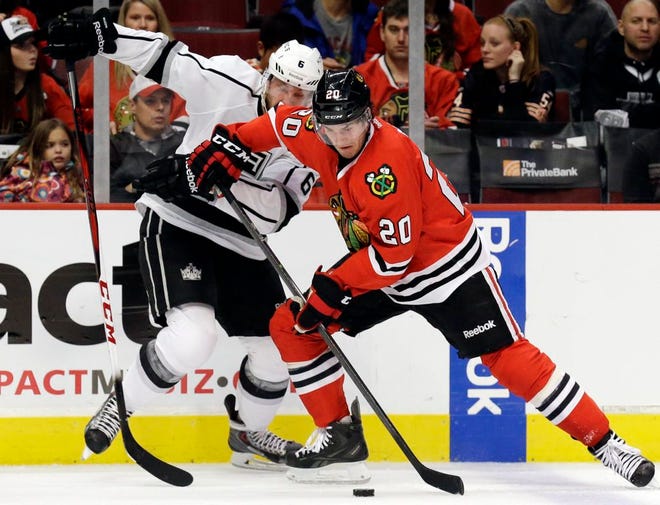 Chicago Blackhawks' Brandon Saad, right, controls the puck against Los Angeles Kings' Jake Muzzin during the second period on Sunday in Chicago. Blackhawks won 3-1.