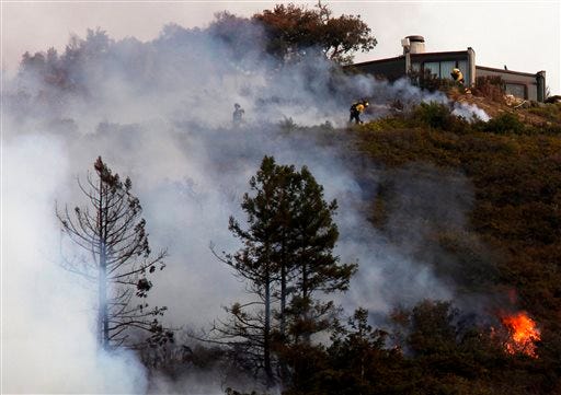 Firefighters defend a home as a wild land fire burns in the Pfeiffer Ridge area in Big Sur, Calif. on Monday.