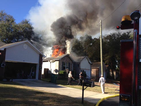 Flames shoot from the roof of a house on Ivy Avenue in Niceville on Tuesday afternoon. Two dogs were rescued and no one was injured.