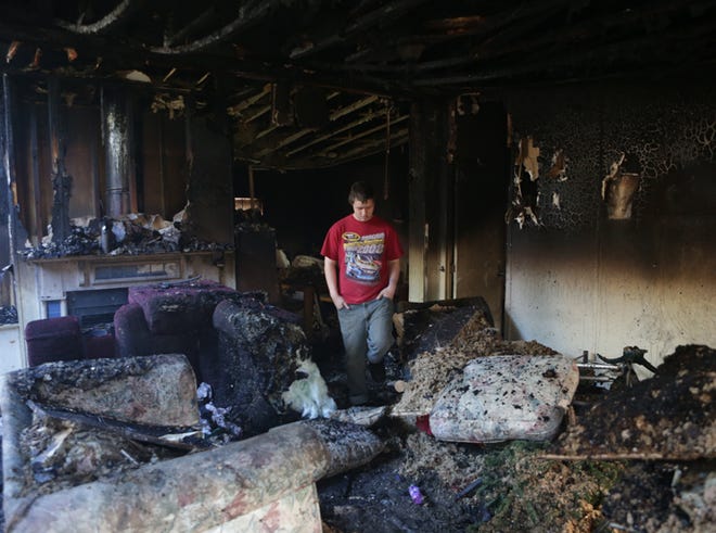 William Harrison stands in the living room of a trailer at the scene of a fire in Callaway on Wednesday.