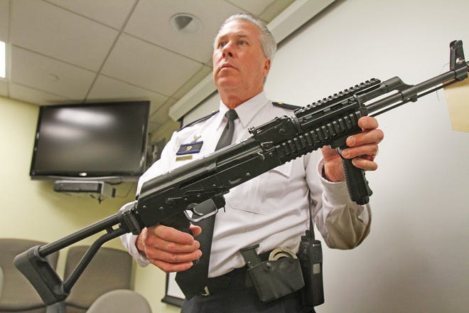 Deputy Chief Thomas Oates III holds one of the 130 illegal firearms Providence police seized in 2012.