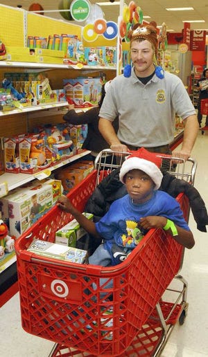 Terry.Dickson@jacksonville.com National Park Service ranger Dan Hovanec pushes Jeremiah Beauford through Target as they look for Christmas gifts during Saturday's Cops and Kids shopping day.