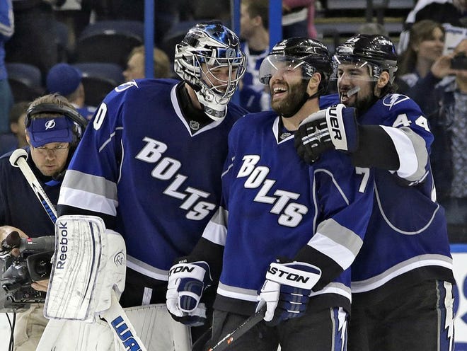 Tampa Bay Lightning defenseman Radko Gudas (7), of the Czech Republic, celebrates with teammates goalie Ben Bishop (30) and center Nate Thompson (44) after Gudas scored an overtime goal against the Carolina Hurricanes during an NHL hockey game, Saturday, Dec. 21, 2013, in Tampa, Fla. (AP Photo/Chris O'Meara)