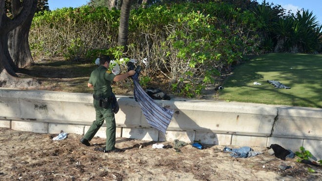 Border Patrol Agent Peter Daniel gathers clothing and personal items left behind by immigrants who landed their boat Friday in the North End. Among the found items were local telephone numbers, identification and a receipt from Grand Bahama Island.