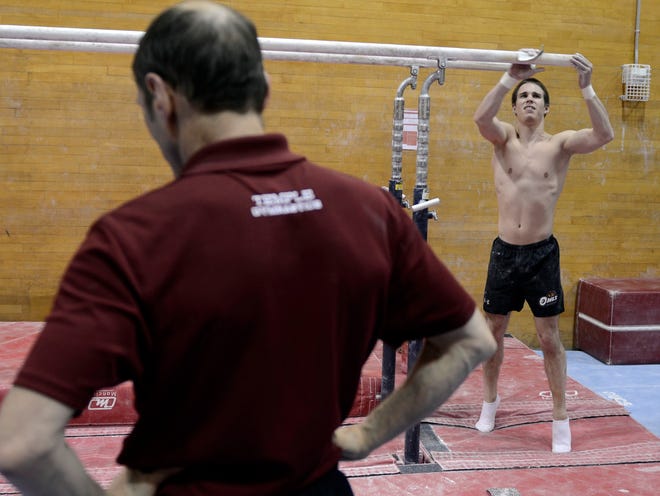 In this Dec. 6, 2013, photo, Temple men's gymnastics coach Fred Turoff pauses while helping student coach Alex Tighe work out, in Philadelphia.