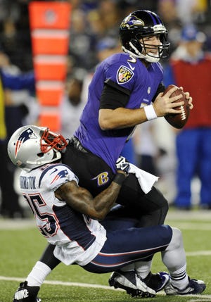 Baltimore Ravens quarterback Joe Flacco, right, is sacked by New England Patriots cornerback Kyle Arrington in the first half of an NFL football game, Sunday in Baltimore.