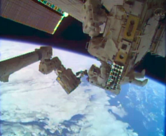 In this image taken from video provided by NASA, astronauts Rick Mastracchio, top, and Michael Hopkins work to repair an external cooling line on the International Space Station on Monday, Dec. 24, 2013, 260 miles above Earth. The external cooling line - one of two - shut down Dec. 11. The six-man crew had to turn off all nonessential equipment, including experiments. (AP Photo/NASA)
