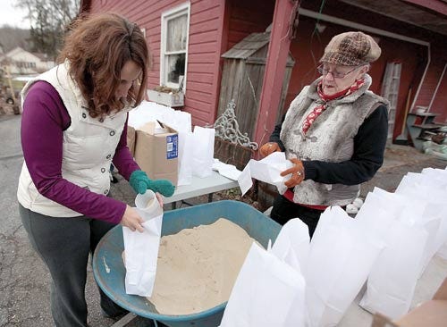Photo by Marie Dirle/ New Jersey Herald Becky Grabowsky, left, and Carolyn Celly fill paper bag luminaries with sand and faux-candles Tuesday in Stillwater.