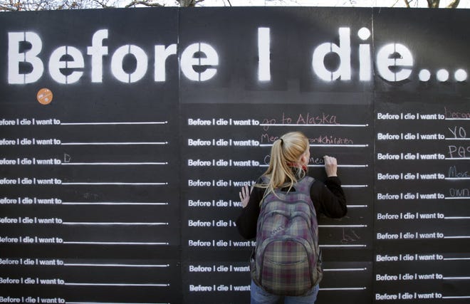 Christina Pakus of New Hampshire writes her hopes in the "Before I Die" installation at Providence's Burnside Park in November.