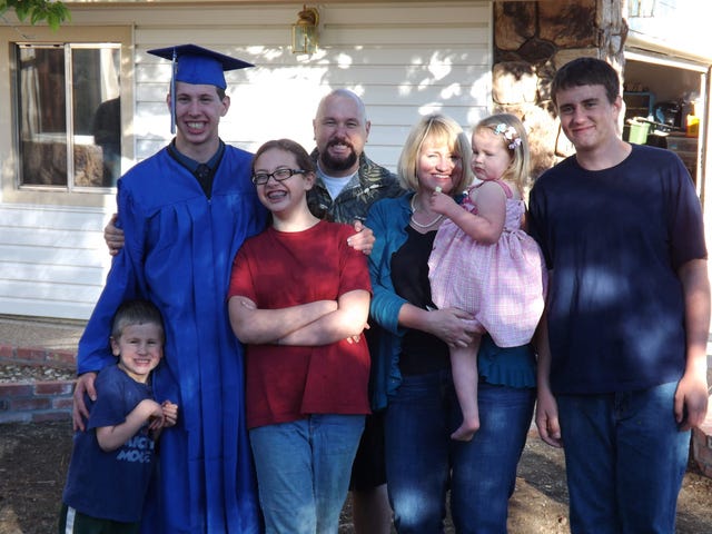 In this June 2012 photo provided by Edwin Lyngar, from left, the Lyngar family, Reagan, 6, Abby, 13, Edwin, 40, Joy, 44, Ellie, 4, and John Zaleschuk, 17, pose at the graduation party for their son, Eddie Lyngar, 19, in cap and gown, in Reno, Nev. Lyngar's eldest son is now in the Air Force and won't make it home for Christmas, but "Santa" will arrive Christmas Day with more presents for the little ones. "You have people moving in and moving out., said Lyngar. "You try to have one day when everyone's together. Whether it's two weeks before or two weeks after, it doesn't matter. That's Christmas." (AP Photo/Courtesy Edwin Lyngar, Cheryl Lyngar)