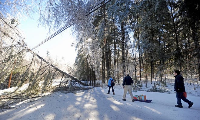 Chris Devine, center, hauls a sled of gifts with his daughter Jordan, 11, left, and stepson Derek Gervais, 20, right, to their home on Maplehurst Lane in Belgrade, Maine on Wednesday, Dec. 25, 2013. The Devine's lost power on Monday and have hauled their supplies in on sled ever since. Trees and power lines are down on both sides of their driveway, luckily they weren't home when the trees fell affording them the opportunity to drive to town for gas and other essentials for life off the grid. Central Maine Power says it could be at least a week before power is restored in rural areas like Belgrade. (AP Photo/Morning Sentinel, Michael G. Seamans)