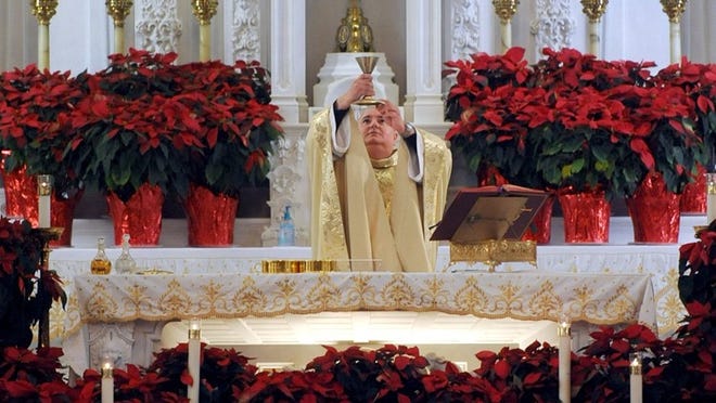 The Rev. Glen J. Pothier prepares to give Holy Communion during Christmas Mass at St. Edward Catholic Church.