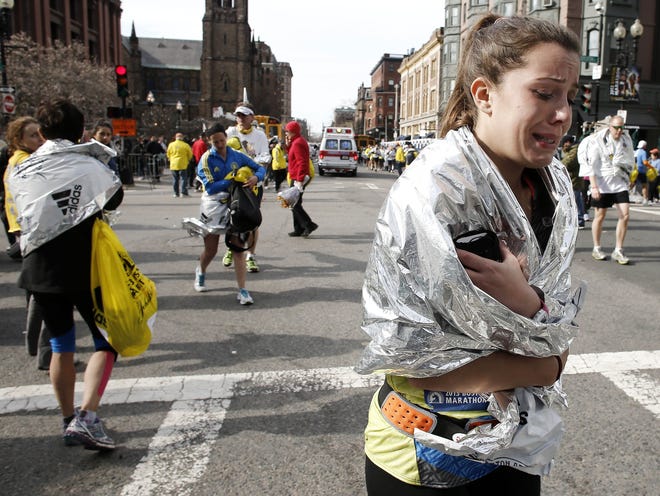 In this Monday, April 15, 2013 file, an unidentified Boston Marathon runner cries as she leaves the course near Copley Square in Boston after two explosions at the finish line. The Boston Marathon bombing has been selected the sports story of the year in an annual vote conducted by The Associated Press.