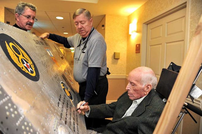 BRUCE.LIPSKY@JACKSONVILLE.COM Richard Harvey (L-R) and Keith Ellefson hold the B-17 wing panel for Captain Walter "Big Dog" Harvey to sign on Thursday, December 26, 2013, in St. Augustine, FL. Ellefson drove from Ozark, Alabama with the wing panel as part of the 384th Bomb Group Veterans Signing Project. Walter Harvey was the co-pilot of the B-17 named "Big Dog" in the 544th Squadron.