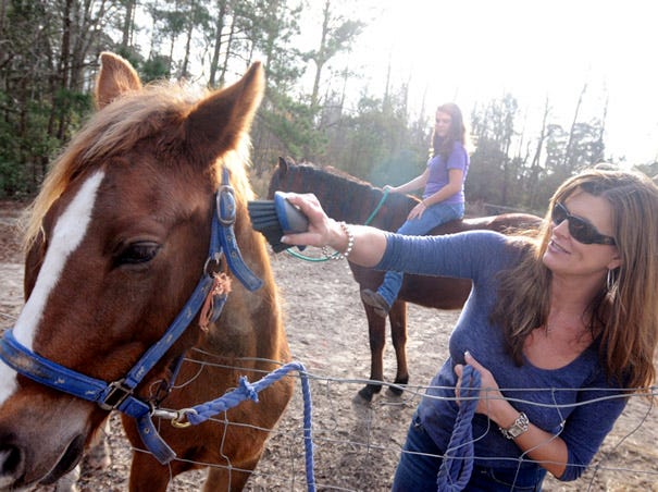 Tammie Morgan Parris brushes her horse named spice while her daughter Morgan Hall, 13 rides Rudy at their Hampstead home Monday.