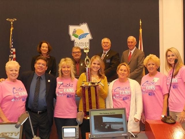 Members of the Chicks with Cans are presented with a trophy by Flagler County commissioners at a recent commission meeting for winning the Feed Flagler team challenge. Back row from left, Flagler County Commissioners: Barbara Revels, George Hanns, Frank Meeker and Charlie Erickson
Front from left, Estelle Spivey, Flagler County Commissioner Nate McLaughlin, Cindy Dalecki, Alexandra Jennings, Danielle Anderson, Marion Poole, Jamie Brown