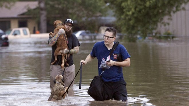 A Manchaca Fire and Rescue volunteer assists a man with two dogs as he slogs through floodwaters on Quicksilver Boulevard in Southeast Austin during the Halloween flood.