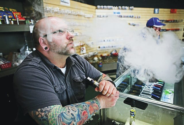 Matt Kostecki, of Milwaukee, who helps out at Milwaukee Vapor, exhales some of the vaporized e-juice from an e-cigarette on Dec. 6. Michael Sears/Milwaukee Journal Sentinel/MCT