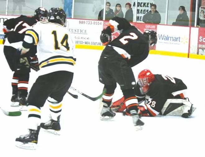 Cheboygan goaltender Kaleb Wood (far right) makes a save in front of teammate Nate Stempky (2) during Saturday's Cheboygan Christmas Showcase contest against Midland Dow.