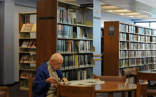 A man reads a newspaper at the DeLand Regional Library on Monday in downtown DeLand.