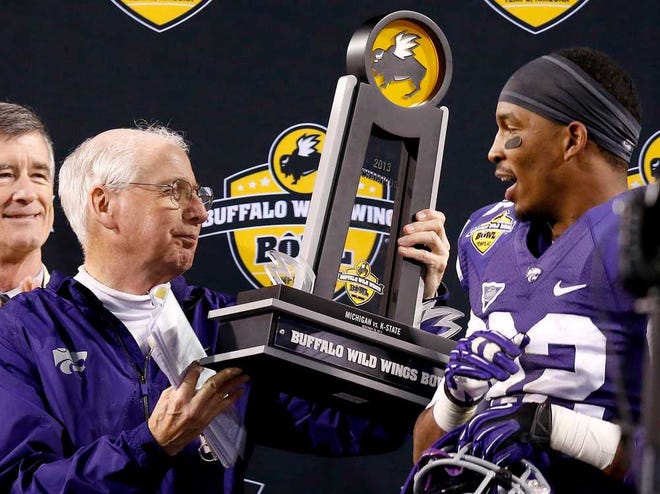 Kansas State head coach Bill Snyder, left, hands the championship trophy to Kansas State's Dante Barnett, right, in post-game ceremonies at the Buffalo Wild Wings Bowl NCAA college football game Saturday, Dec. 28, 2013, in Tempe, Ariz. Kansas State defeated Michigan 31-14. (AP Photo/Ross D. Franklin)