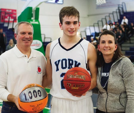 York High School senior center Aaron Todd poses with his parents following last February's Western Maine Class B quarterfinal basketball game against Greely where he scored his 1,000th career point.