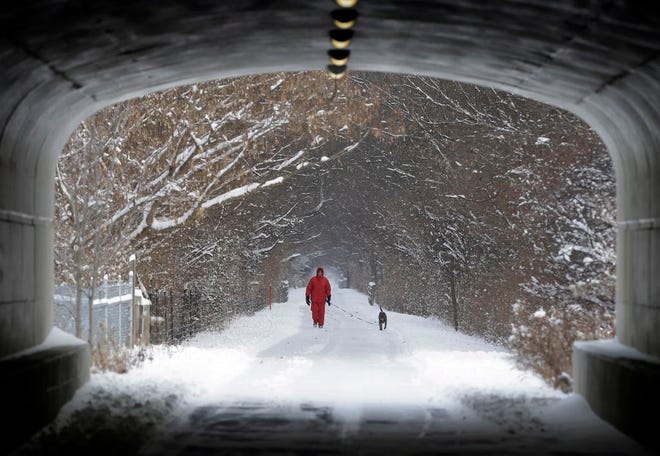 Naoom Haimson walks his dog, Molly, on the snow covered Monon Trail in Carmel, Ind., Thursday, Jan. 2, 2014. Over 5 inches of snow fell in Central Indiana. (AP Photo/Michael Conroy)