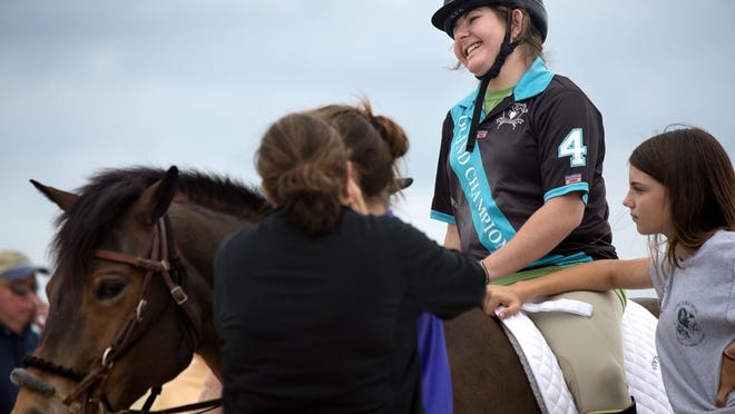 Reed Gutner, 19, center, of Boynton Beach sits on her horse, while Haley Keller, 12, right, of Wellington holds the horse still before a polo match with riders from Vinceremos Therapeutic Riding Center and Grand Champions Polo Club on Saturday, January 4, 2014 on the beach in Palm Beach Shores. The event was a fundraiser for Vinceremos which provides equine therapy for people with physical, cognitive and emotional disabilities. (Madeline Gray/The Palm Beach Post)