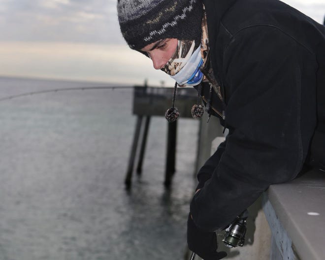 James Cude bundles up to stay warm while fishing at the county pier on Saturday.