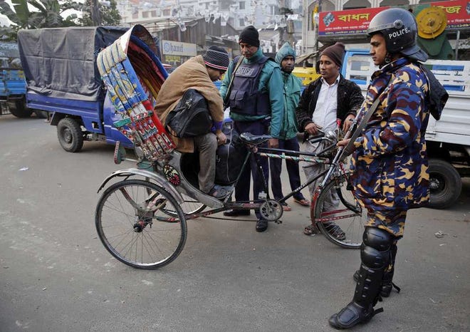 Bangladeshi policemen check passengers riding on a rickshaw during a nationwide 48-hour strike called by the main opposition Bangladesh Nationalist Party (BNP) a day before general elections in Dhaka, Bangladesh, Saturday, Jan. 4, 2014. The run-up to Sunday's general election in Bangladesh has been marked by bloody street clashes and caustic political vendettas, and the vote threatens to plunge this South Asian country even deeper into crisis. (AP Photo/Rajesh Kumar Singh)
