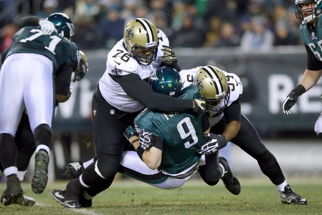 Philadelphia's Nick Foles (9) is tackled by New Orleans' Akiem Hicks (76) and Cameron Jordan (94) during the second half of Saturday's NFC wildcard playoff game in Phildelphia.