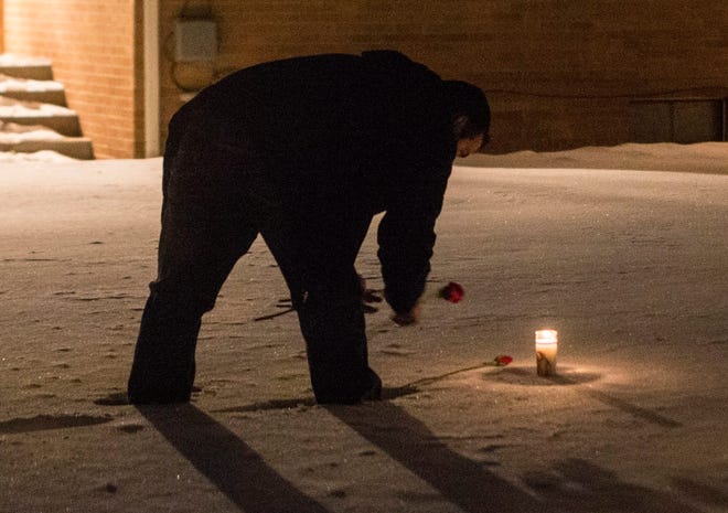 Patrick Cashatt places a candle and five roses Tuesday for the family members he lost a year ago, Jan. 7, 2013, at 1625 10th Ave. in Rockford. BRENT LEWIS/RRSTAR.COM