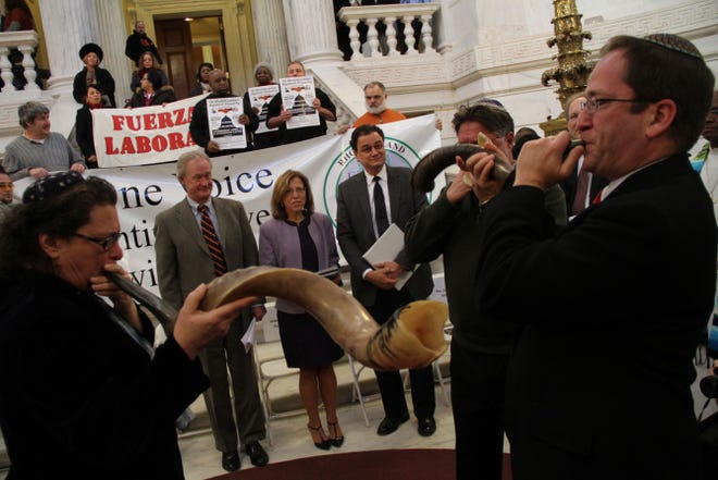 Rabbi Amy Levin, Rabbi Alan Flam and Rabbi Peter Stein, right, blow shofars to call the community to assembly Wednesday during an interfaith prayer vigil at the State Huouse to implore elected officials to fight poverty in Rhode Island. Looking on are Governor Chafee, left, Senate President M. Teresa Paiva Weed and Speaker of the House Gordon Fox.