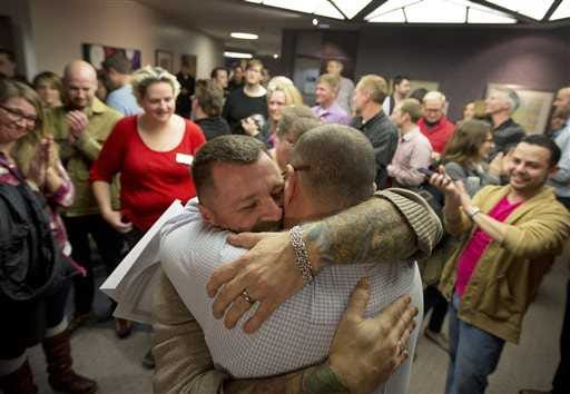 Chris Serrano, left, and Clifton Webb embrace after being married, as people wait in line to get licenses outside of the marriage division of the Salt Lake County Clerk's Office in Salt Lake City. The Supreme Court on Monday put same-sex marriages on hold in Utah, at least while a federal appeals court more fully considers the issue.
