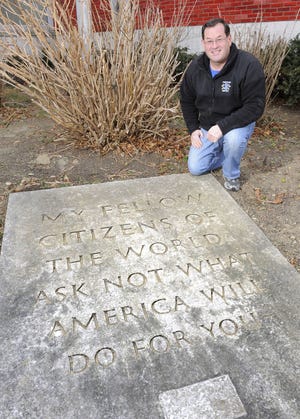 Gerry Willis, dean of students at Salve Regina University, kneels next to the stone marker he discovered in 1986 while working at the Boys & Girls Clubs of Newport County in Middletown. The marker and the club are now located in Newport.
