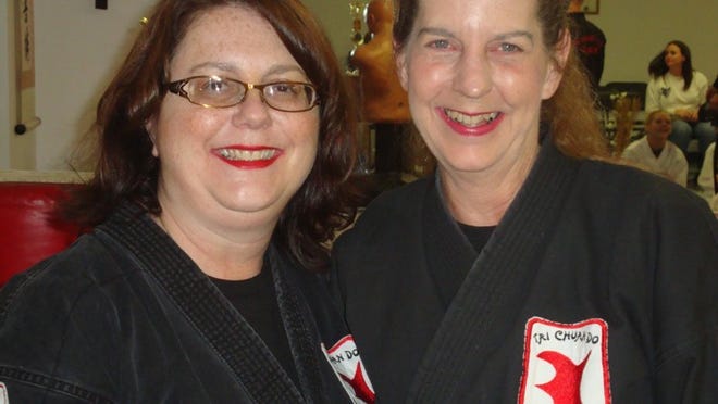 Mary Hills (left) and Laurie Keahey are martial arts students at LaSala’s Dojo who earned their first-degree black belts in 2013. Hills, 49, did it despite bouts with breast cancer and other health ailments; Keahey, 60, is the oldest person ever to earn the belt at LaSala’s. (Photo by BILL MEREDITH)