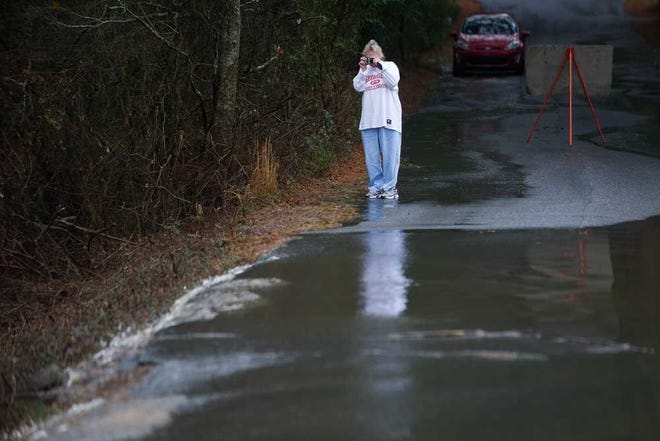 A woman stops to take a photograph of a flooded portion of Lakeview Drive in Oglethorpe County, near Winterville, Ga., Saturday, Jan. 11, 2014. Lakes on each side of the road flooded together across the road (AJ Reynolds/Staff, @ajreynoldsphoto)