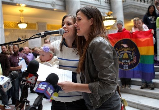 Megan, left, and Candace Berrett, right, hold their daughter Quinn as they speak to supporters of gay marriage during a rally at the Utah State Capitol Friday, Jan. 10, 2014 in Salt Lake City. Supporters of gay marriage filled the rotunda for a rally and to deliver a petition with over 58,000 signatures in support of gay marriage to Utah Governor Gary Herbert.